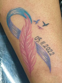 a tattoo with a blue ribbon and a bird on it