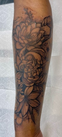 a black and grey flower tattoo on the leg