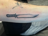 a tattoo of a knife on a person's forearm